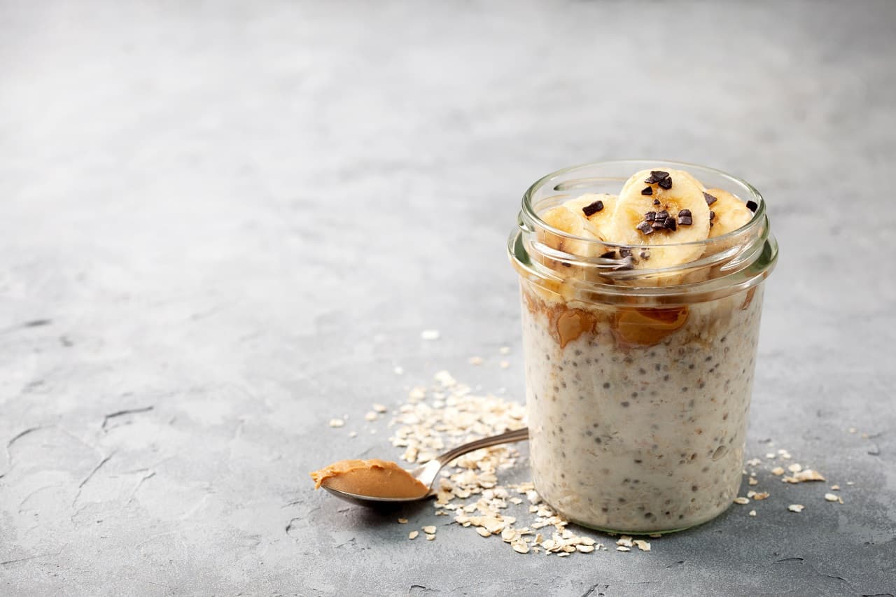 overnight oatmeal with chia seeds, bananas, peanut butter, honey, chocolate sprinkling in a glass jar